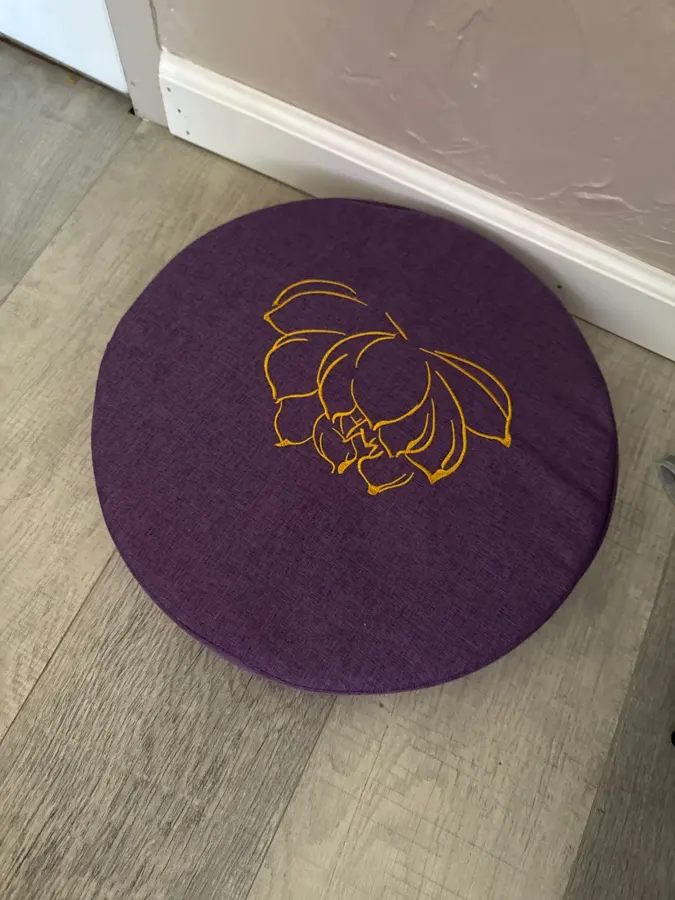 Buyer photo of a dark purple StillSeat meditation cushion on a wood floor
